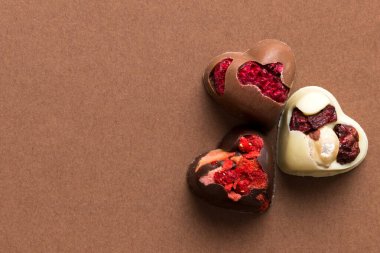 chocolate sweets in the form of a heart with fruits and nuts on a colored background. top view with space for text, holiday concept.
