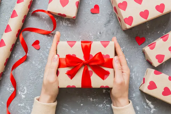 Give a gift on Valentine Day.Valentine gift. Beauty Woman hands holding Gift box with red bow over holiday background.