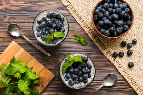 Sağlıklı kahvaltı ve chia tohumlu vanilyalı puding ve böğürtlenli masa arkası, vejetaryen gıda, diyet ve sağlık konsepti. Hindistan cevizi sütü ve yabanmersinli Chia pudingi..