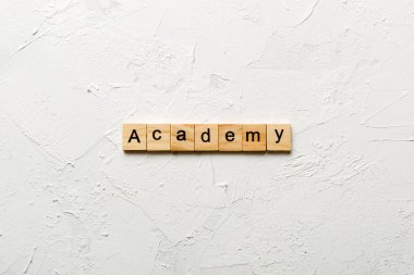 Ahşap blokta ACADEMY kelimesi yazıyor. Çimento masasındaki ACADEMY metni desing, konsept için.