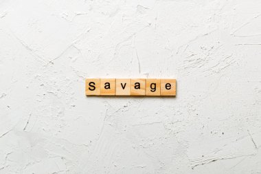 Tahta bloğa yazılmış SAVAGE kelimesi. Çimento masasındaki SAVAGE metni desing, konsept için.