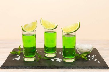 Tatlı ferahlatıcı nane likörü, masa arkasında buz ve nane yaprakları, limon dilimi ve nane aromalı shot.