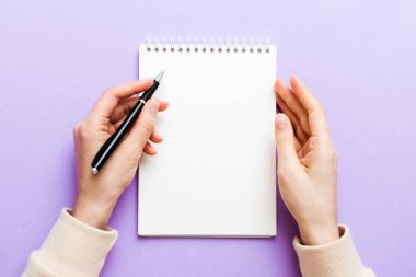 Defterine kalem yazan kadın eli. Ofis masasında çalışan bir kadın. Kalem ve çizim defterini tutan kadın. Model Konsepti.