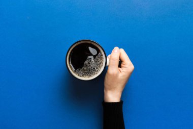 Renkli arka planda bir fincan kahve tutan minimalist stil bir kadın. Düz yerde, kapuçino bardağının üstünde. Metin için boş yer, kopyalama alanı. Kahve bağımlılığı. Üst manzara, düz uzanma.