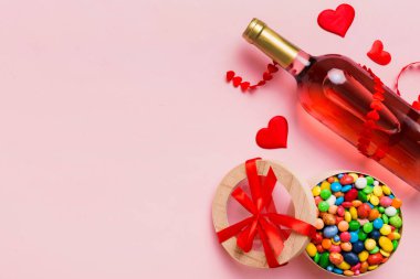 Sevgililer Günü için renkli arka planda bir şişe kırmızı şarap hediye ve çikolatalı. Kalp, hediye kutusuyla şekillendirilmiş çikolatalar fotokopi alanı ile üst görünüm.