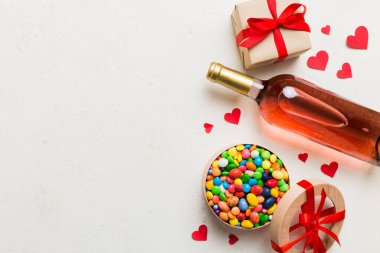 Sevgililer Günü için renkli arka planda bir şişe kırmızı şarap hediye ve çikolatalı. Kalp, hediye kutusuyla şekillendirilmiş çikolatalar fotokopi alanı ile üst görünüm.