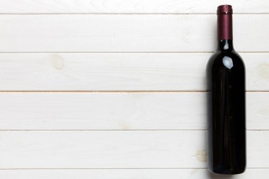 Renkli masada bir şişe kırmızı şarap. Düz konum, üst görünüm kopyalama alanı.