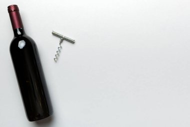 Renkli masada tirbuşonlu bir şişe kırmızı şarap. Düz konum, üst görünüm kopyalama alanı.