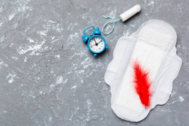 Alarm saatini hijyenik kadın tamponları ve regl pedleri ile çalıyor. Tıbbi konsept kadın kritik günler ve regl dönemi. Kadın günlük hijyen. Boşluğu kopyala.