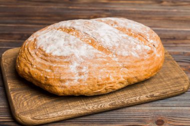 Tahtanın üzerinde beyaz ahşap zemine karşı taze pişmiş ekmek. Ekmeği kopyalama alanı ile perspektif görünümü.