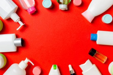 Plastik vücut bakım şişesi çerçevesi düz kompozisyonda renkli arka plan boşluğunda sizin tasarımınız için kozmetik ürünler sergileniyordu. Beyaz Kozmetik kapları kümesi, kopya alanı ile üst görünüm.