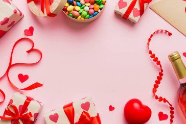 top view photo of st valentine day decor shopping, bag, wine, bottle, envelope, gift, box, candy and red heart on colored background with empty space. Frame background.