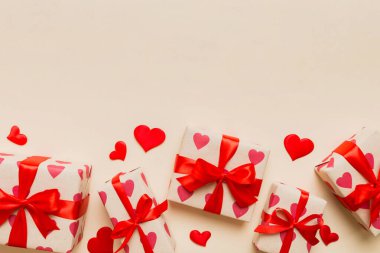 Top view photo of valentine day decorations gift box with red ribbon bow on colored background. Holiday gift boxes with top view.