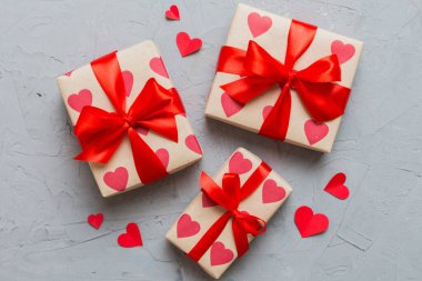 Top view photo of valentine day decorations gift box with red ribbon bow on colored background. Holiday gift boxes with top view.