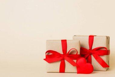 gift box with red bow and red heart on colored background. Perspective view. Flat lay.