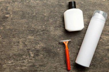 Tıraş Adam seti. Traş makinesi, havlu, losyon ve renkli arka planda tıraş köpüğü. Erkekler banyo aksesuarları üst görünüm.