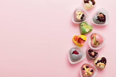 chocolate sweets in the form of a heart with fruits and nuts on a colored background. top view with space for text, holiday concept.