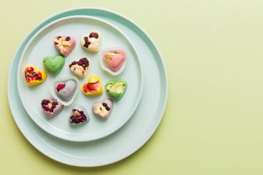 Plate with different chocolate on colored background. Assortment of fine chocolates top view vith copy space Health and obesity concept.