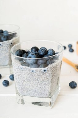 Sağlıklı kahvaltı ve chia tohumlu vanilyalı puding ve böğürtlenli masa arkası, vejetaryen gıda, diyet ve sağlık konsepti. Hindistan cevizi sütü ve yabanmersinli Chia pudingi..