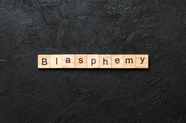 Tahta blokta BLASPHEmy kelimesi yazıyor. Beton masa üzerindeki BLASPHEMY metin desing, konsept için.