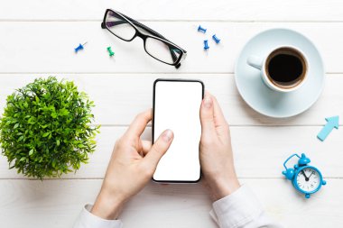 Mesajınız veya bilgi içeriğiniz için boş bir kopya ekranı olan akıllı telefonları tutan kadın ellerinin üst görünümü. üst görünümde telefon beyaz ekranı kullanan kadın eli.