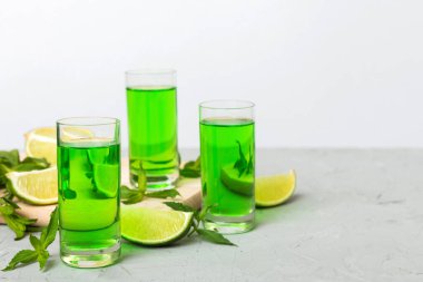 Tatlı ferahlatıcı nane likörü, masa arkasında buz ve nane yaprakları, limon dilimi ve nane aromalı shot.