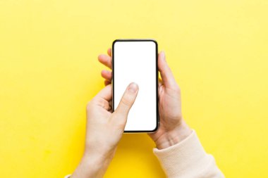 Mesajınız veya bilgi içeriğiniz için boş bir kopya ekranı olan akıllı telefonları tutan kadın ellerinin üst görünümü. üst görünümde telefon beyaz ekranı kullanan kadın eli.
