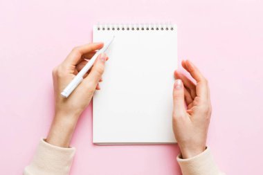 Defterine kalem yazan kadın eli. Ofis masasında çalışan bir kadın. Kalem ve çizim defterini tutan kadın. Model Konsepti.