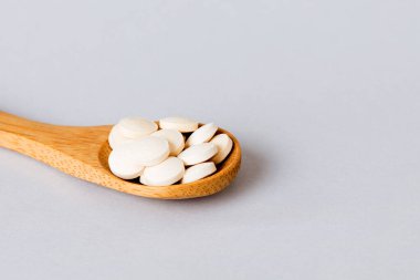 Heap of white pills on colored background. Tablets scattered on a table. Pile of red soft gelatin capsule. Vitamins and dietary supplements concept.