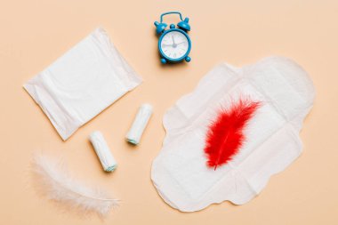 Alarm saatini hijyenik kadın tamponları ve regl pedleri ile çalıyor. Tıbbi konsept kadın kritik günler ve regl dönemi. Kadın günlük hijyen. Boşluğu kopyala.
