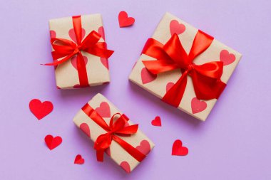 Top view photo of valentine day decorations gift box with red ribbon bow on colored background. Holiday gift boxes with top view.