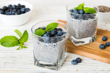 Sağlıklı kahvaltı ve chia tohumlu vanilyalı puding ve böğürtlenli masa arkası, vejetaryen gıda, diyet ve sağlık konsepti. Hindistan cevizi sütü ve yabanmersinli Chia pudingi..