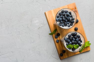 Sağlıklı kahvaltı ve chia tohumlu vanilyalı puding ve böğürtlenli masa arkası, vejetaryen gıda, diyet ve sağlık konsepti. Hindistan cevizi sütü ve yabanmersinli Chia pudingi..