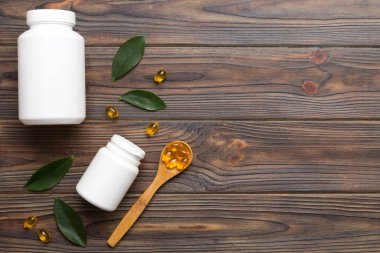 Omega-3 kapsülleri yeşil yapraklı arka planda beyaz bir şişede yatar. Balık yağı tabletleri. Biyolojik olarak aktif katkı maddeleri. Omega 6, Omega 9, A vitamini, E, D vitamini, D3 vitamini..