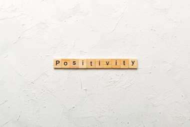 positivity word written on wood block. positivity text on cement table for your desing, concept. clipart