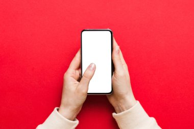 Mesajınız veya bilgi içeriğiniz için boş bir kopya ekranı olan akıllı telefonları tutan kadın ellerinin üst görünümü. üst görünümde telefon beyaz ekranı kullanan kadın eli.