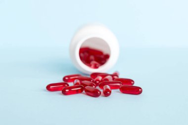 Red pills spilled around a pill bottle. Medicines and prescription pills flat lay background. Red medical capsules.