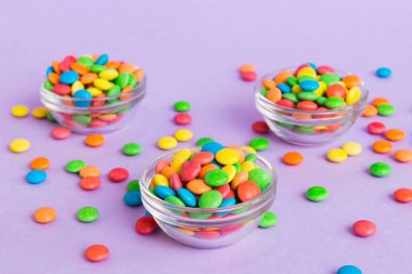 Renkli arka planda bir kasede çok renkli şekerler. Doğum günü ve tatil konsepti. Kopyalama alanı olan üst görünüm.