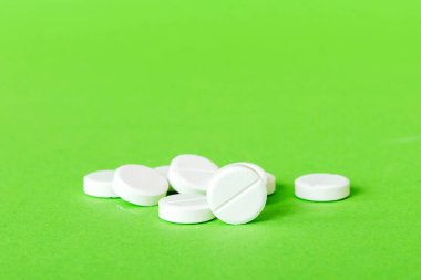 Renkli arka planda bir yığın beyaz hap. Tabletler masaya saçılmış. Kırmızı yumuşak jelatin kapsül yığını. Vitaminler ve beslenme takviyeleri konsepti.