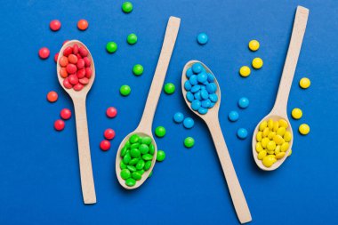 Renkli arka planda kaşık üzerinde renkli tatlı şekerler. Fotokopi alanı ile şekerleme dekoru üst görünümü.
