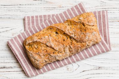 Renkli bir masada buğday ve glüten ile taze somunlar. Peçetedeki ekmek kırsal arka planda, taze ekmek üst görünümü.