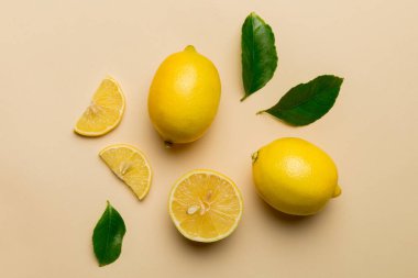 Renkli arka planda yeşil yapraklı taze limonlar, üst görünüm, metin için boşluk.