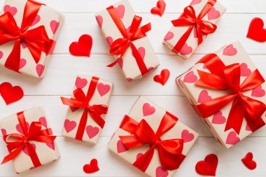 Top view photo of valentine day decorations gift box with red ribbon bow on colored background. Holiday gift boxes with top view.