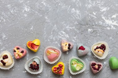 chocolate sweets in the form of a heart with fruits and nuts on a colored background. top view with space for text, holiday concept.