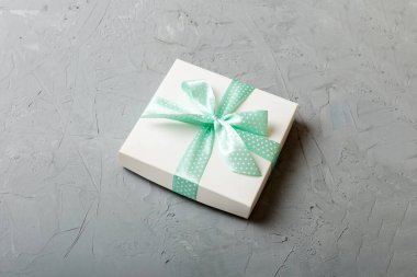Renkli arka planda mor kurdeleli Noel ya da diğer tatil hediyelerini kağıda sardım. Şimdiki kutu, renkli tabloda hediye süslemesi, kopya alanı ile üst görünüm.