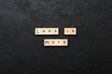 less is more word written on wood block. less is more text on table, concept. clipart