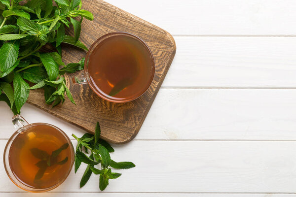 Чашка мятного чая на фоне стола. Зеленый чай со свежим мятным видом сверху с копировальным пространством.