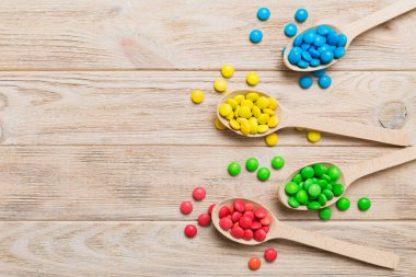 Renkli arka planda kaşık üzerinde renkli tatlı şekerler. Fotokopi alanı ile şekerleme dekoru üst görünümü.