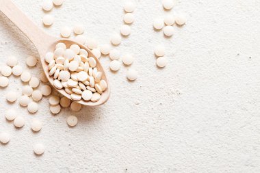 Renkli arka planda bir yığın beyaz hap. Tabletler masaya saçılmış. Kırmızı yumuşak jelatin kapsül yığını. Vitaminler ve beslenme takviyeleri konsepti.