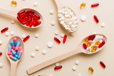 Renkli bir arka planda kaşıkta vitamin kapsülleri. Haplar sağlıklı bir yemek olarak sunuldu. Kırmızı yumuşak jel vitamin takviye kapsülleri kaşık üzerinde.